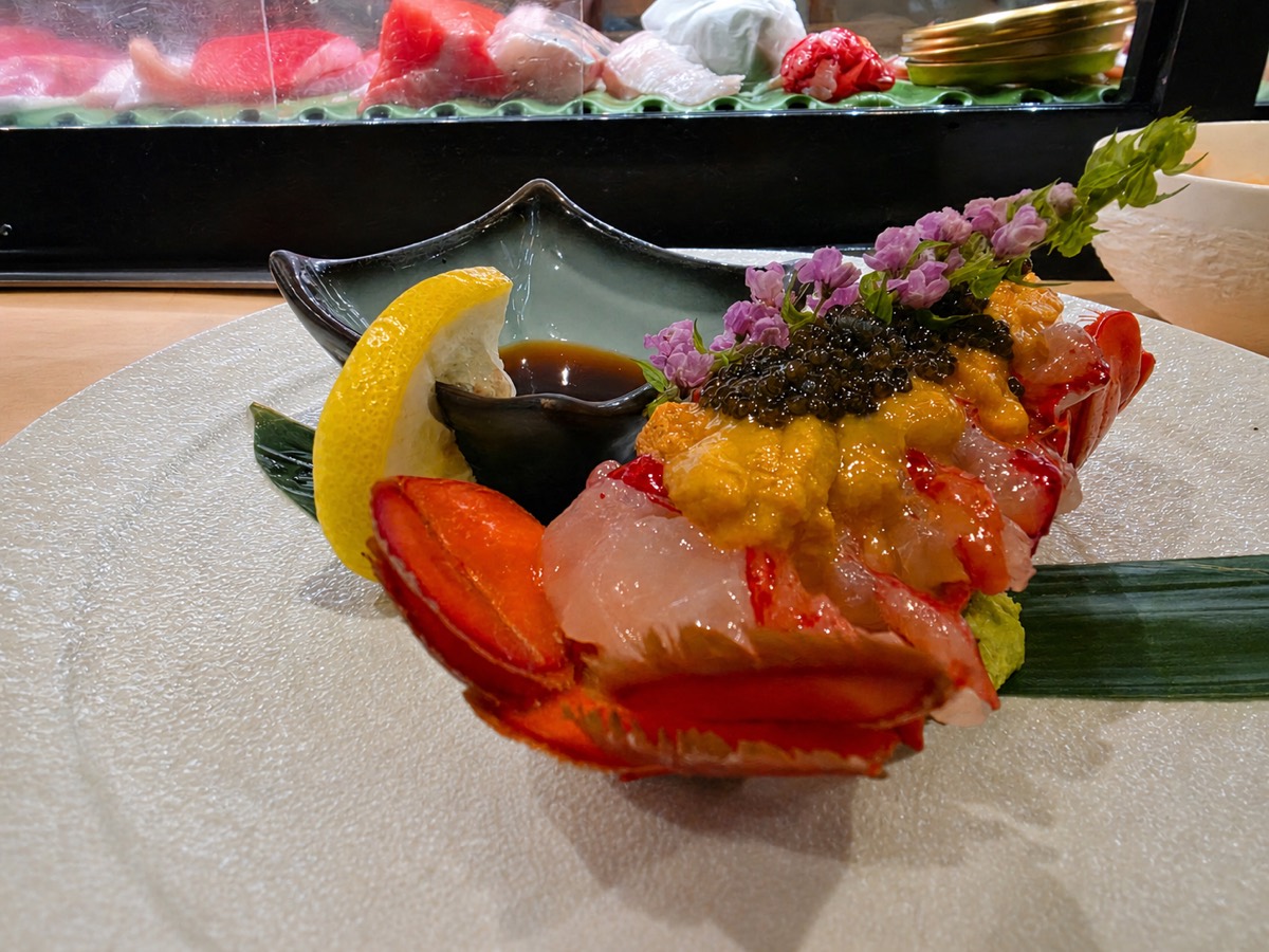 Lobster sashimi presentation topped with sea urchin and caviar, served at the sushi bar